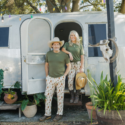Dad wearing Cowboy Christmas Bamboo Men's Lounge Pants while standing beside a vintage camper with mo