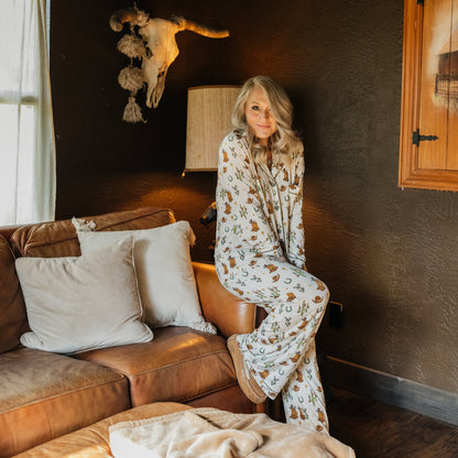 Full-length view of woman modeling Cowboy Christmas Bamboo Button Down Pajama Set in a Western-inspired bedroom.