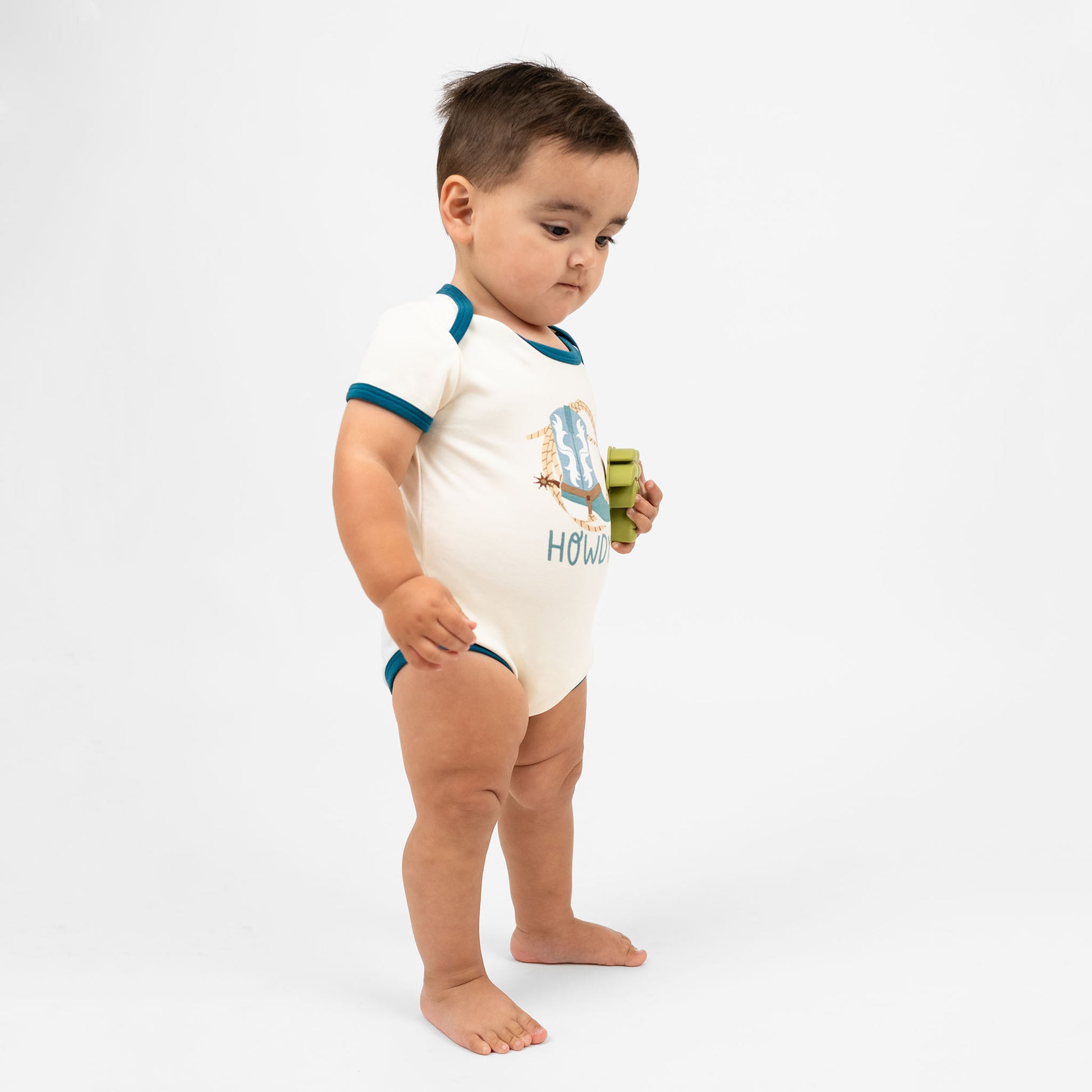 Baby boy wearing our Howdy cotton onesie featuring the word "Howdy" in playful, blue letters, perfect for a western outfit.