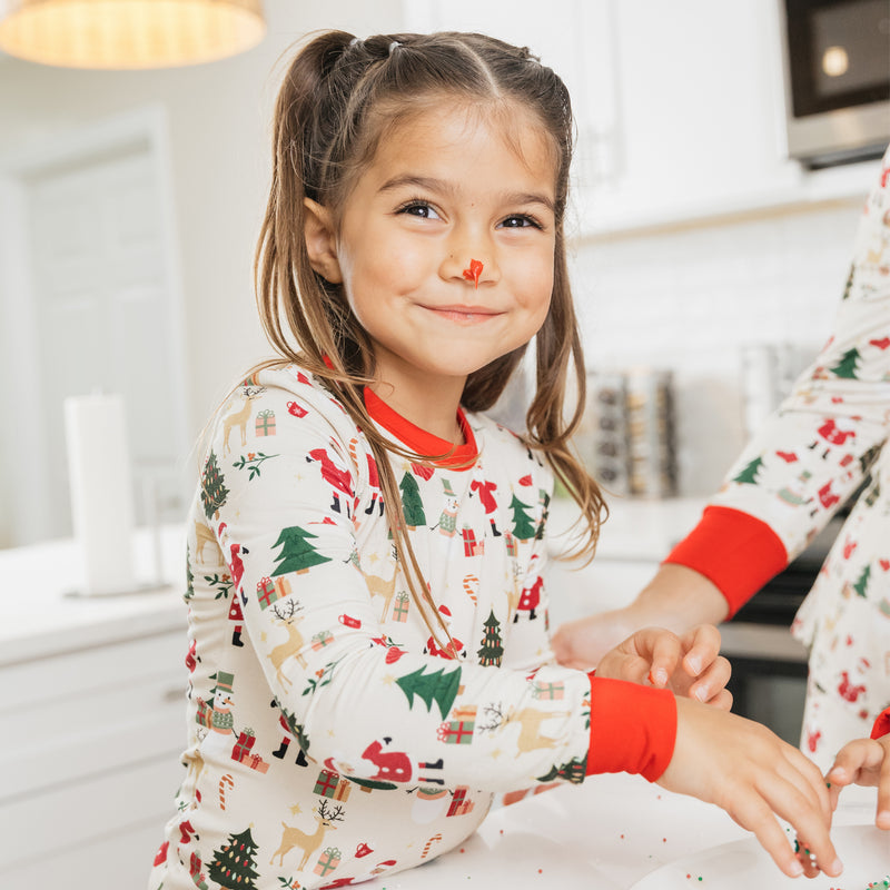Close-up of a smiling girl in Cozy Christmas bamboo pajamas with red cuffs and a festive holiday print.