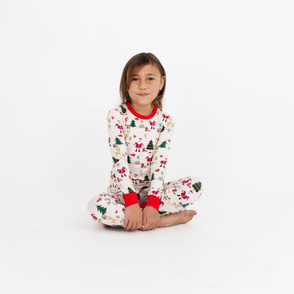 Girl sitting on the floor in Cozy Christmas bamboo pajamas, highlighting the soft, stretchy bamboo fabric and holiday print.
