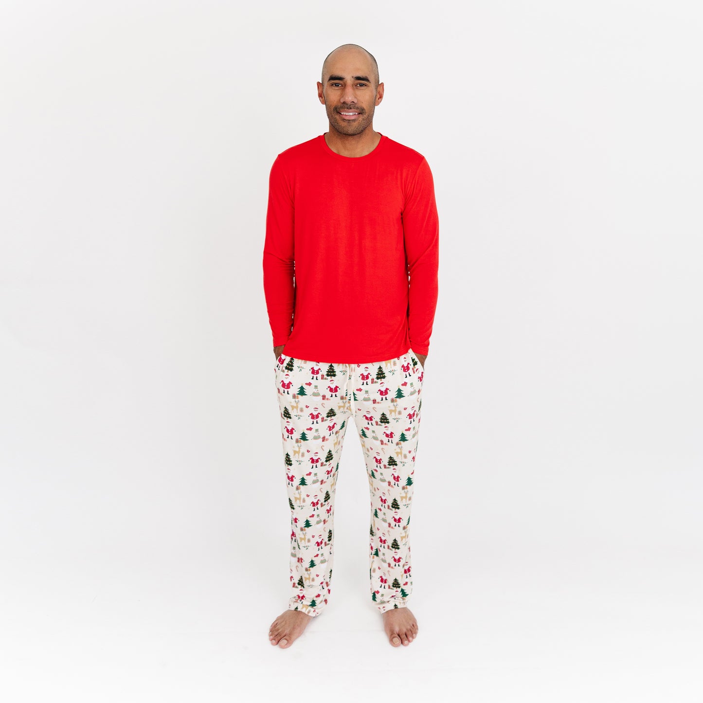 Man wearing Cozy Christmas bamboo relaxed fit pants with red cuffs and festive print stands in studio.