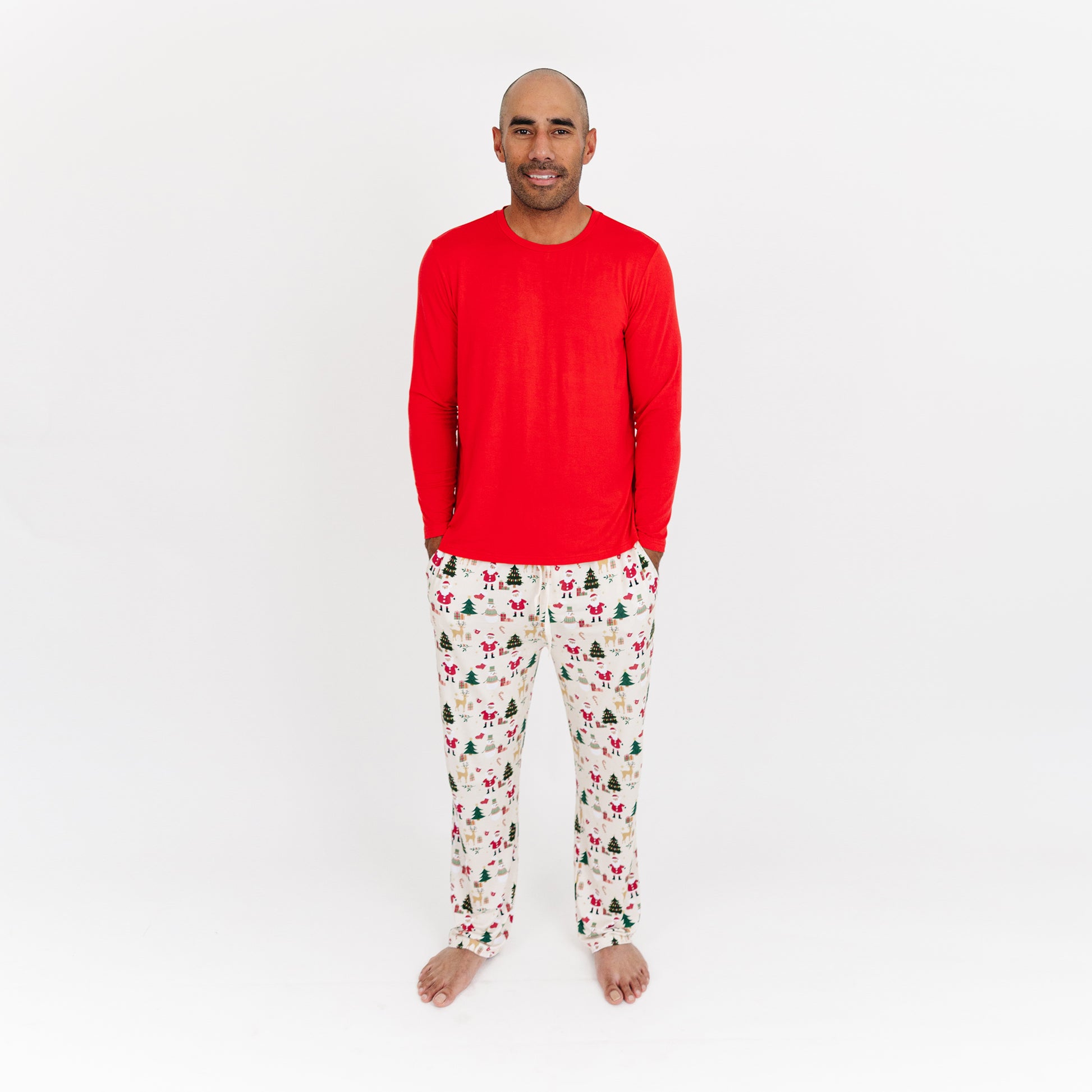Man wearing Cozy Christmas bamboo relaxed fit pants with red cuffs and festive print stands in studio.