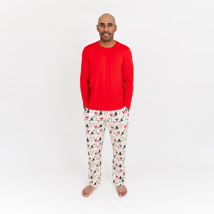 Man wearing Cozy Christmas bamboo relaxed fit pants with red cuffs and festive print stands in studio.