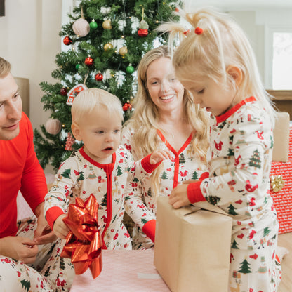 Family in Cozy Christmas bamboo pajamas gathers by the tree to open gifts, showcasing festive prints and cozy comfort.