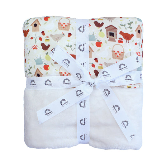 Emerson and Friends Cozy Cottage Twin Camping Bamboo and Fleece Throw Blanket, featuring a soft bamboo top with a charming farmhouse print of chickens, birdhouses, and apples, paired with plush white fleece for extra warmth and comfort.