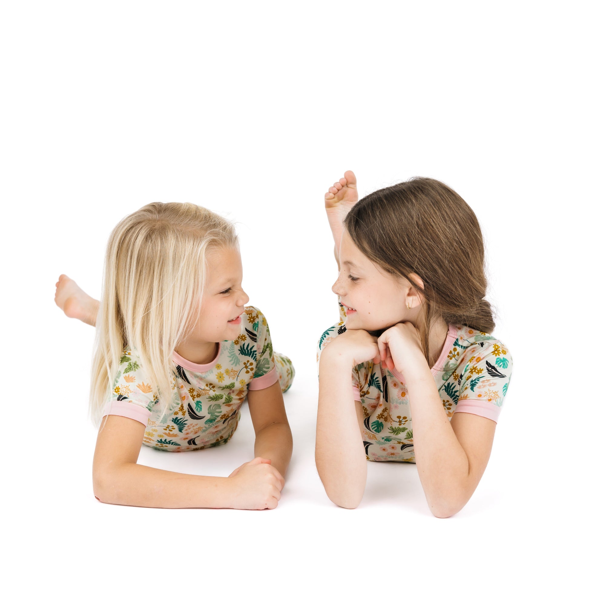 Siblings laying down in moisture-wicking Tropical Blooms bamboo pajamas, showing the comfortable, stretchy fit.