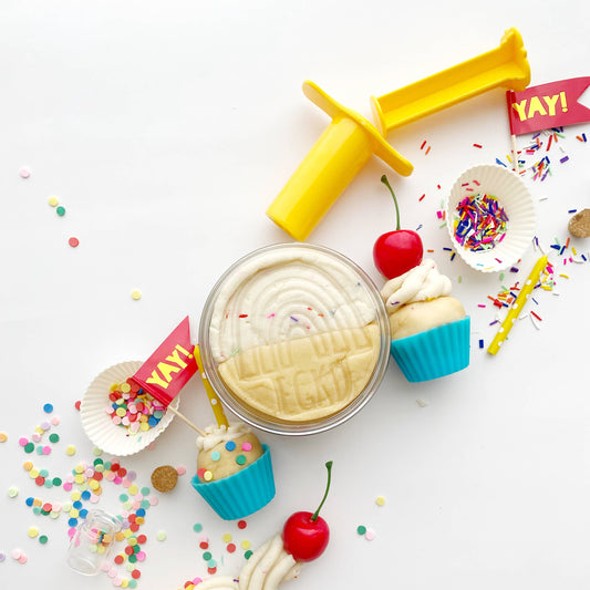 Decorative cake batter with toy airplane, cherry, and cupcake on a white background
