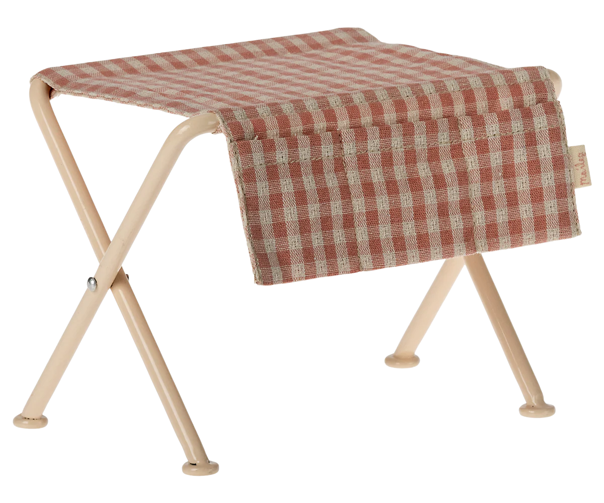 Folding table with a red and beige checkered cover on a white background