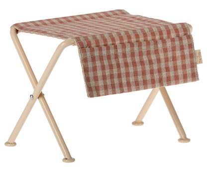 Folding table with a red and beige checkered cover on a white background