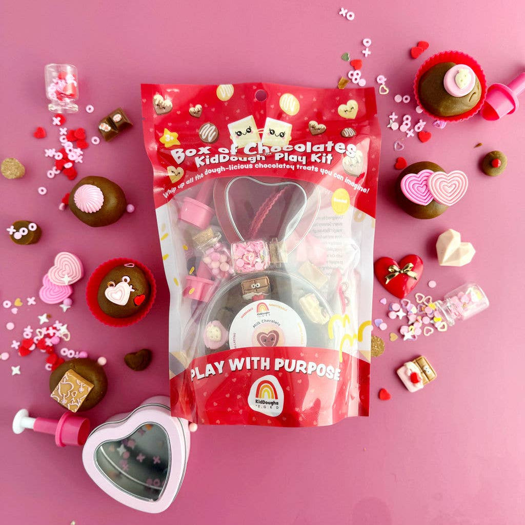 Red packaging of a play kit with various small toys and items on a pink background