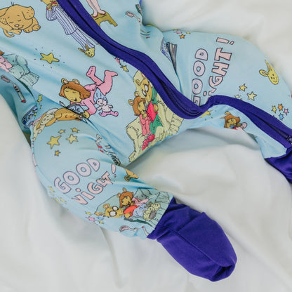 A close-up of the double zipper convertible pajama from our PBS Good Night Arthur™ collaboration, featuring a cozy bedtime scene with Arthur and friends, storybooks, toothbrushes, bunny slippers, a sleeping puppy, crescent moons with sleep caps, twinkling stars, and the words "GOOD NIGHT!" on a soft blue background.