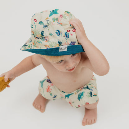 Close up of our Emerson and Friends Coral Reef Reversible Bucket Hat, featuring a vibrant underwater-inspired design with sharks, sea turtles, and coral, offering sun protection and a stylish, adjustable fit for kids and toddlers.