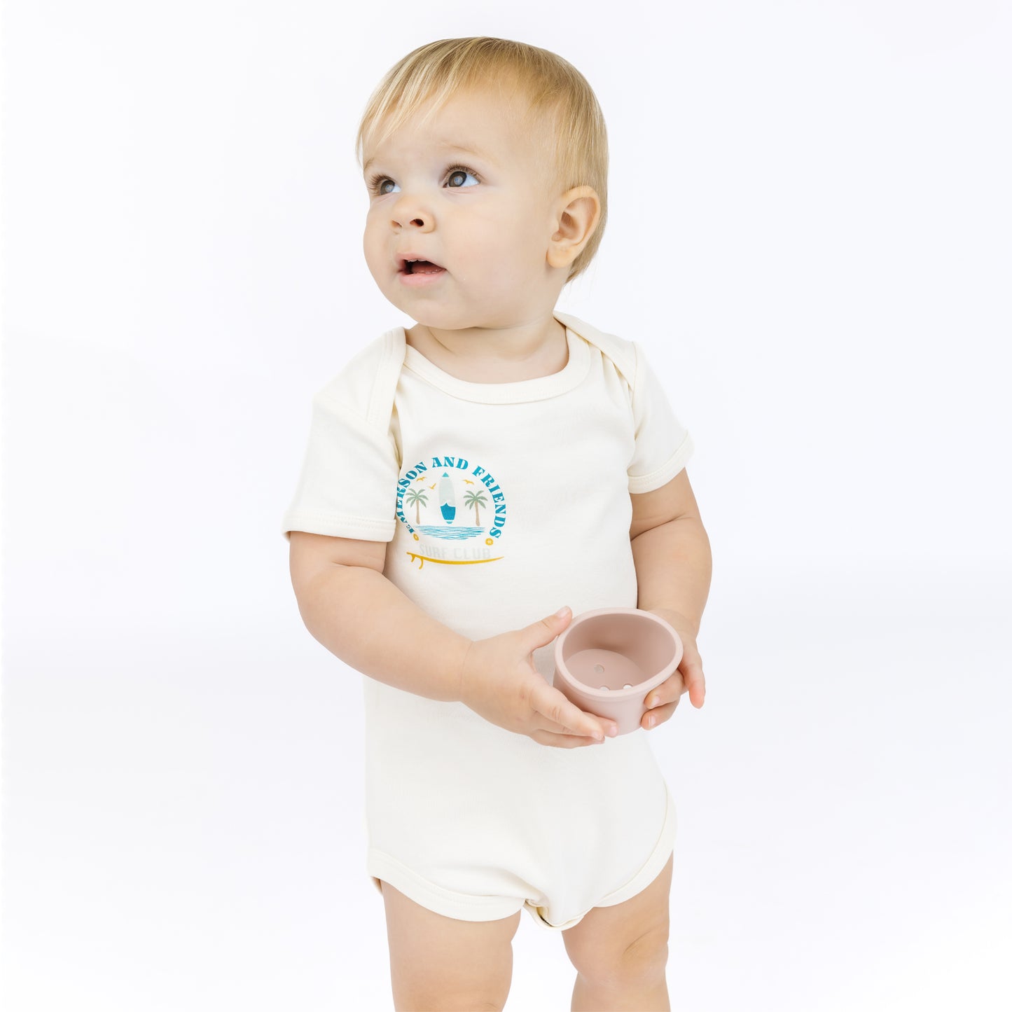 Baby wearing a white bodysuit with a blue graphic and text on a white background