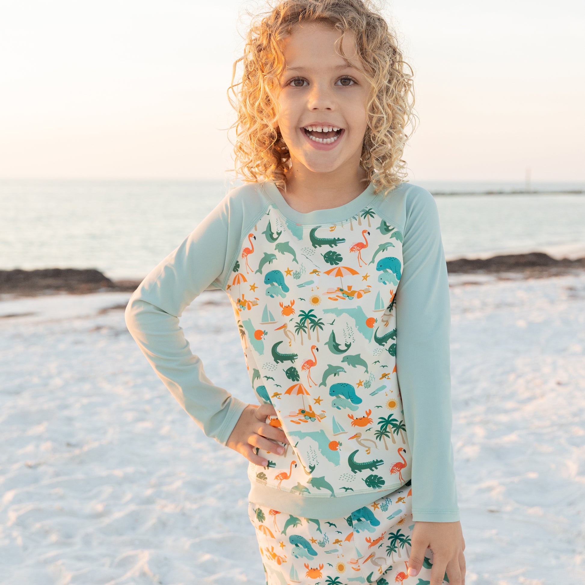 Child wearing a long-sleeve shirt with animal prints on a beach