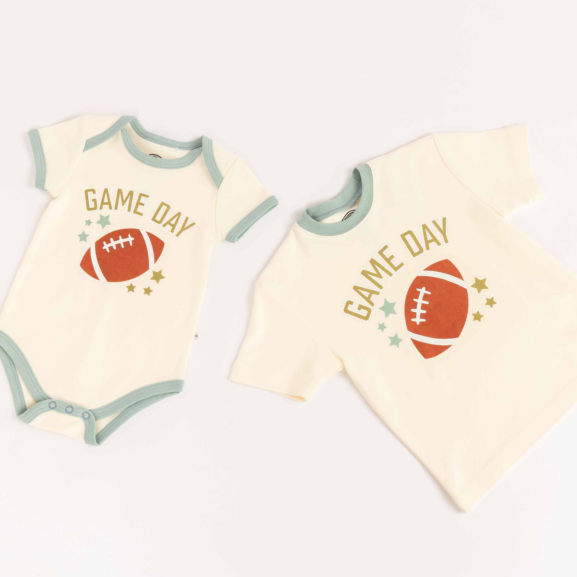 Flatlay of bamboo tee-shirt, and ba,boo onesie laying on white background. Both say "Game Day" with a football on them