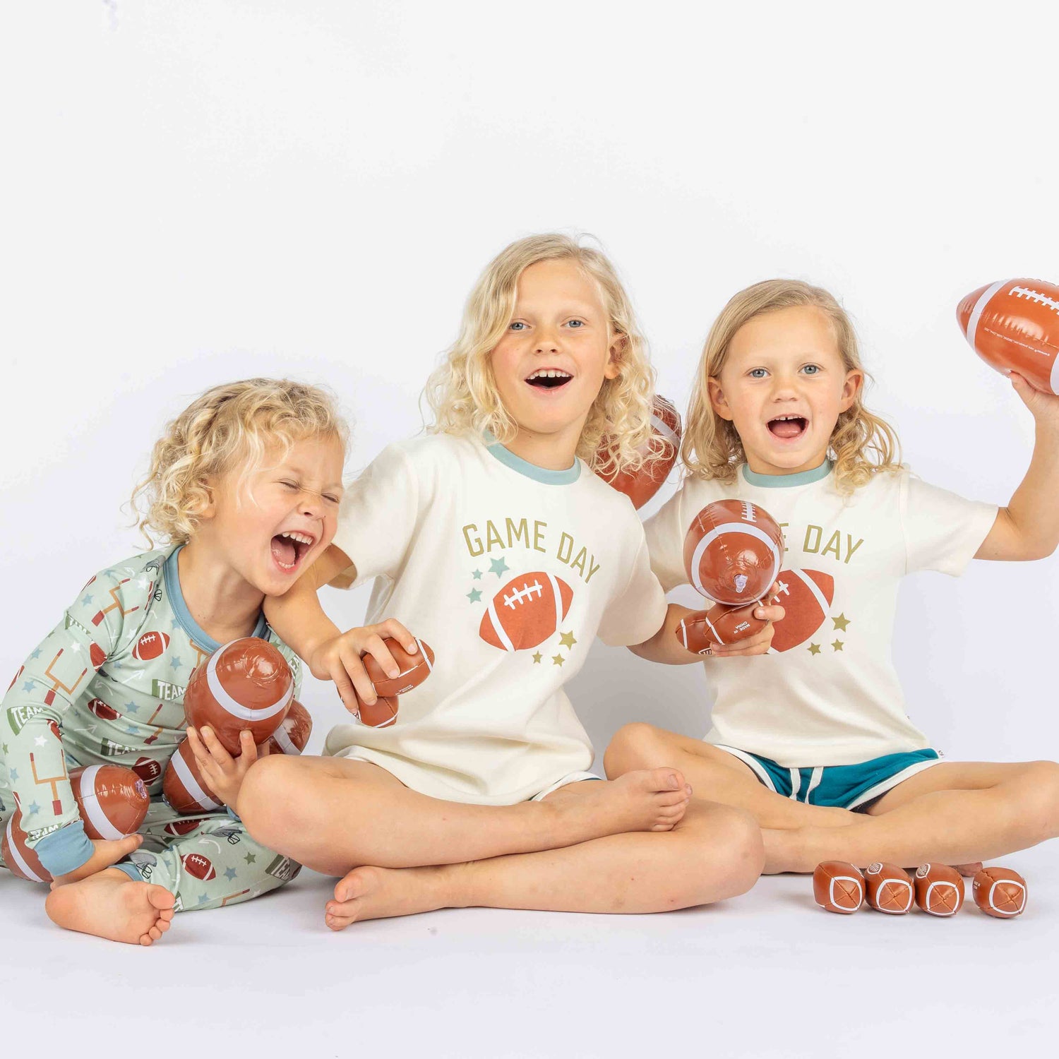 Three Kids holding a footballs while modeling blue and white ringer tee with phrase :Game Day" on it. 