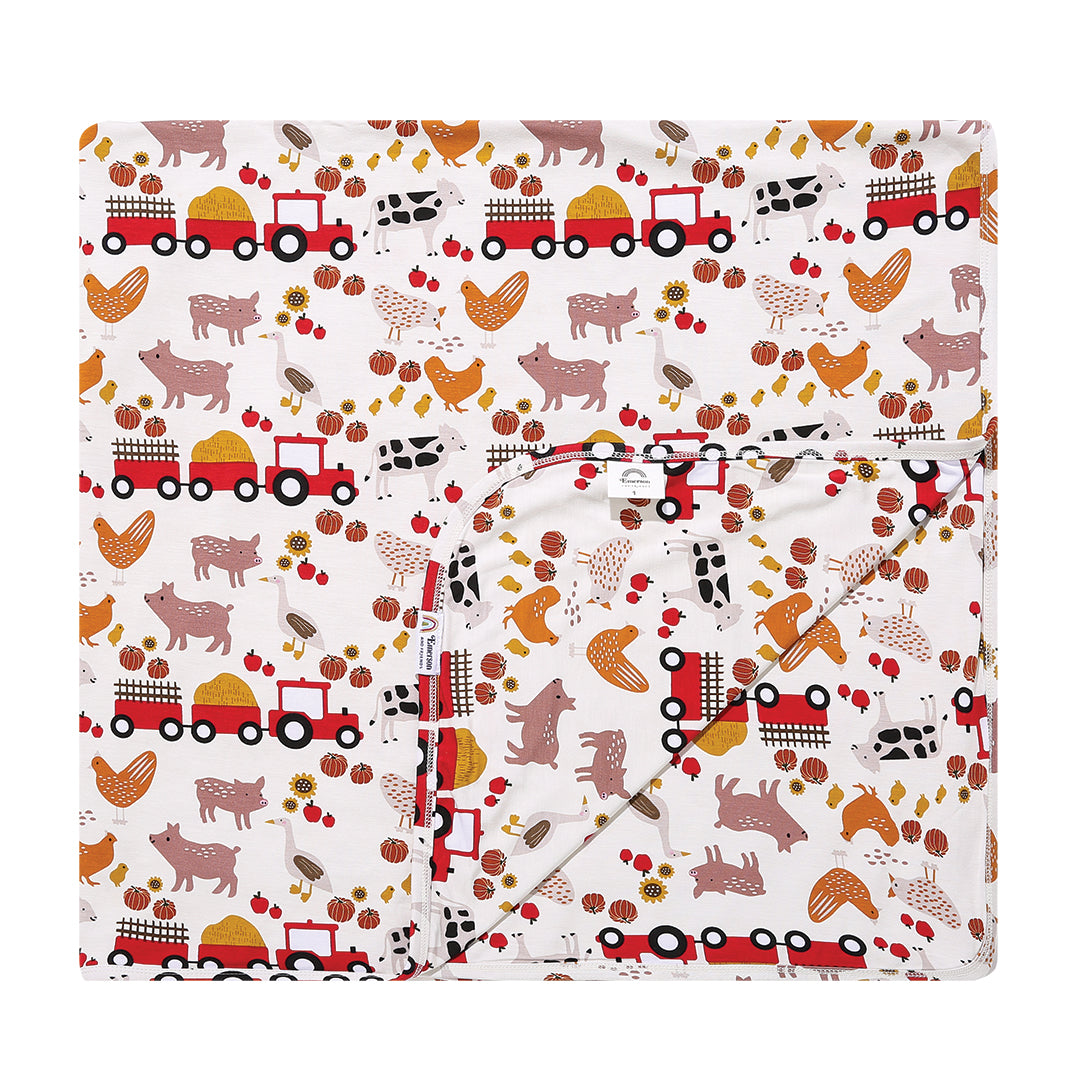 the "farm friends" bamboo blanket. the "farm friends" print is a collection of chickens, roosters, pigs, bails of hay, tractors, chicks, apples, and pumpkins. it's a white background and flashed of reds, yellows, and oranges, to bring out the farm aesthetic.