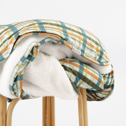 plaid blanket print with white fleece lining on rattan stool with white background.