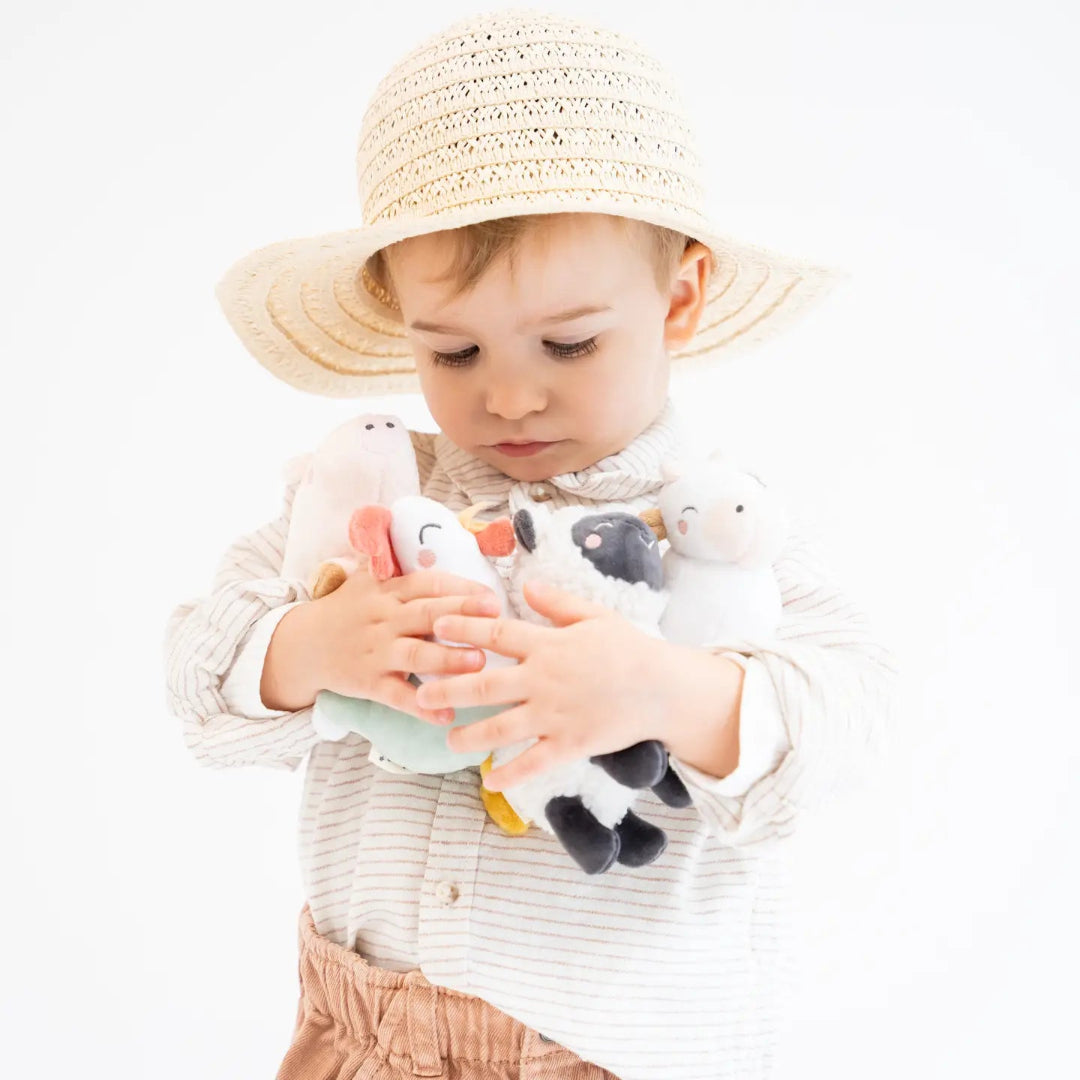 little boy holding farm stuffed animal rattles