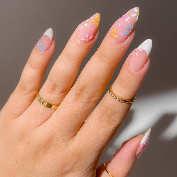 Hand with decorated nails and gold rings on a neutral background