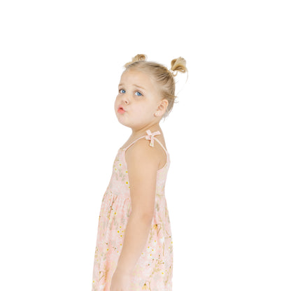 Young girl wearing a light pink dress with floral patterns on a white background