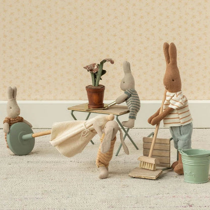 Miniature scene with toy bunnies engaged in cleaning activities on a wooden floor.