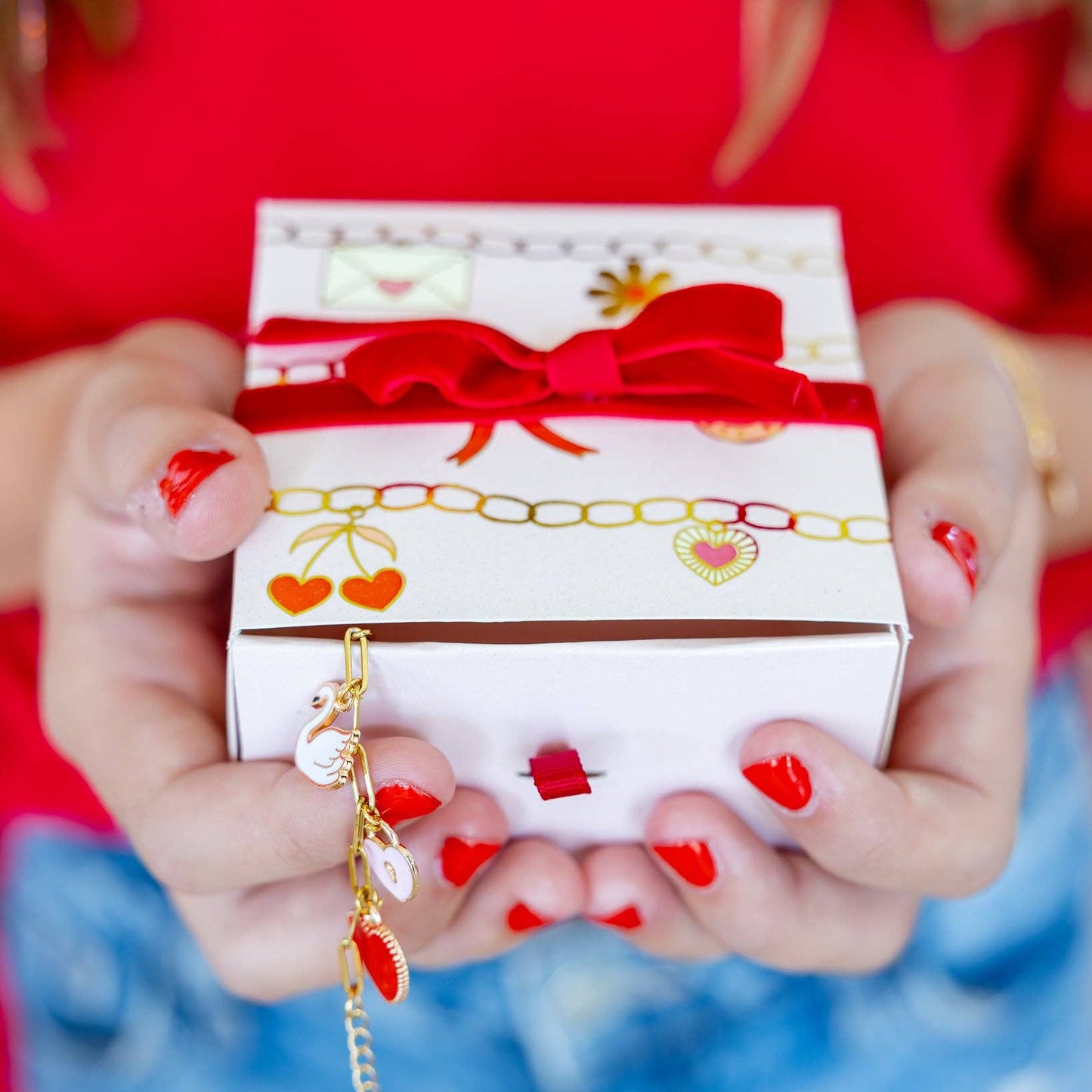 Person holding a gift box with a red ribbon against a blurred background