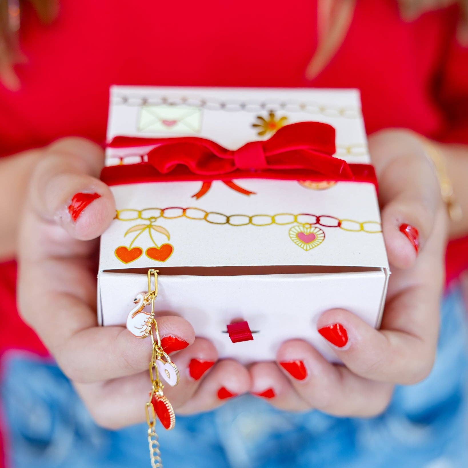 Person holding a gift box with a red ribbon against a blurred background