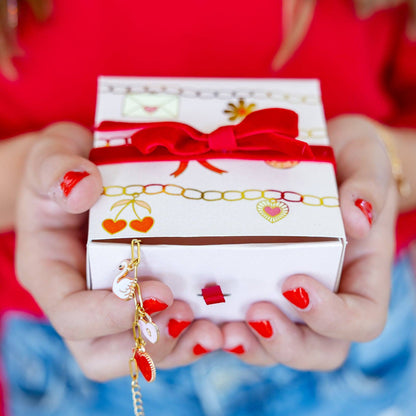 Person holding a gift box with a red ribbon against a blurred background