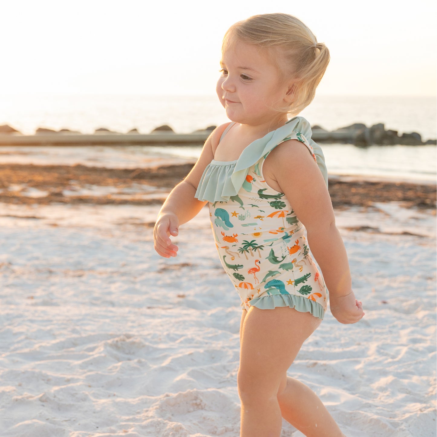 Side profile of a girl wearing the Explore Florida swimsuit, showing the sweet ruffle detail on the neckline and leg openings.