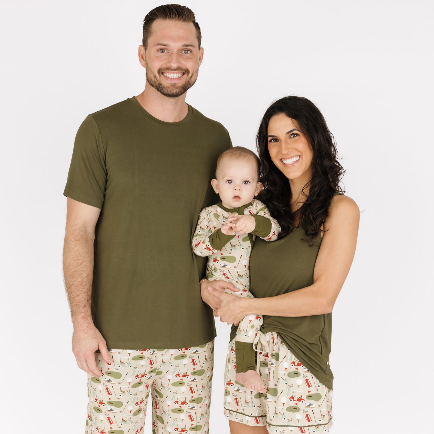 Family of three wearing matching pajamas against a white background