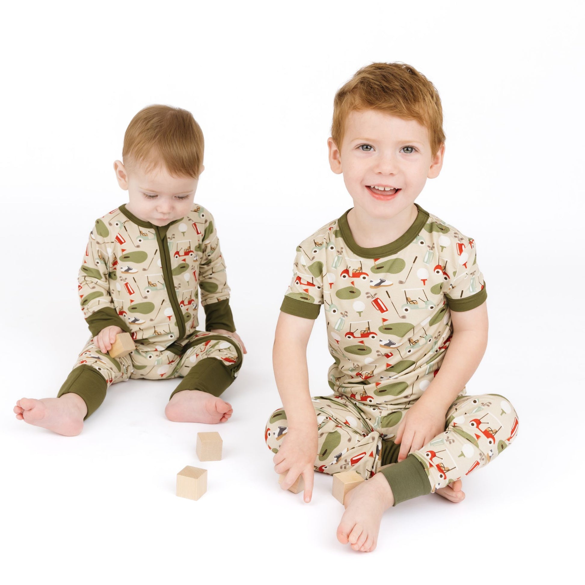 Two children wearing matching pajamas with a nature-themed design on a white background