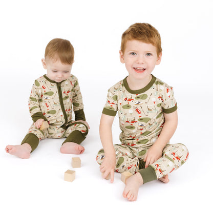 Two children wearing matching pajamas with a nature-themed design on a white background