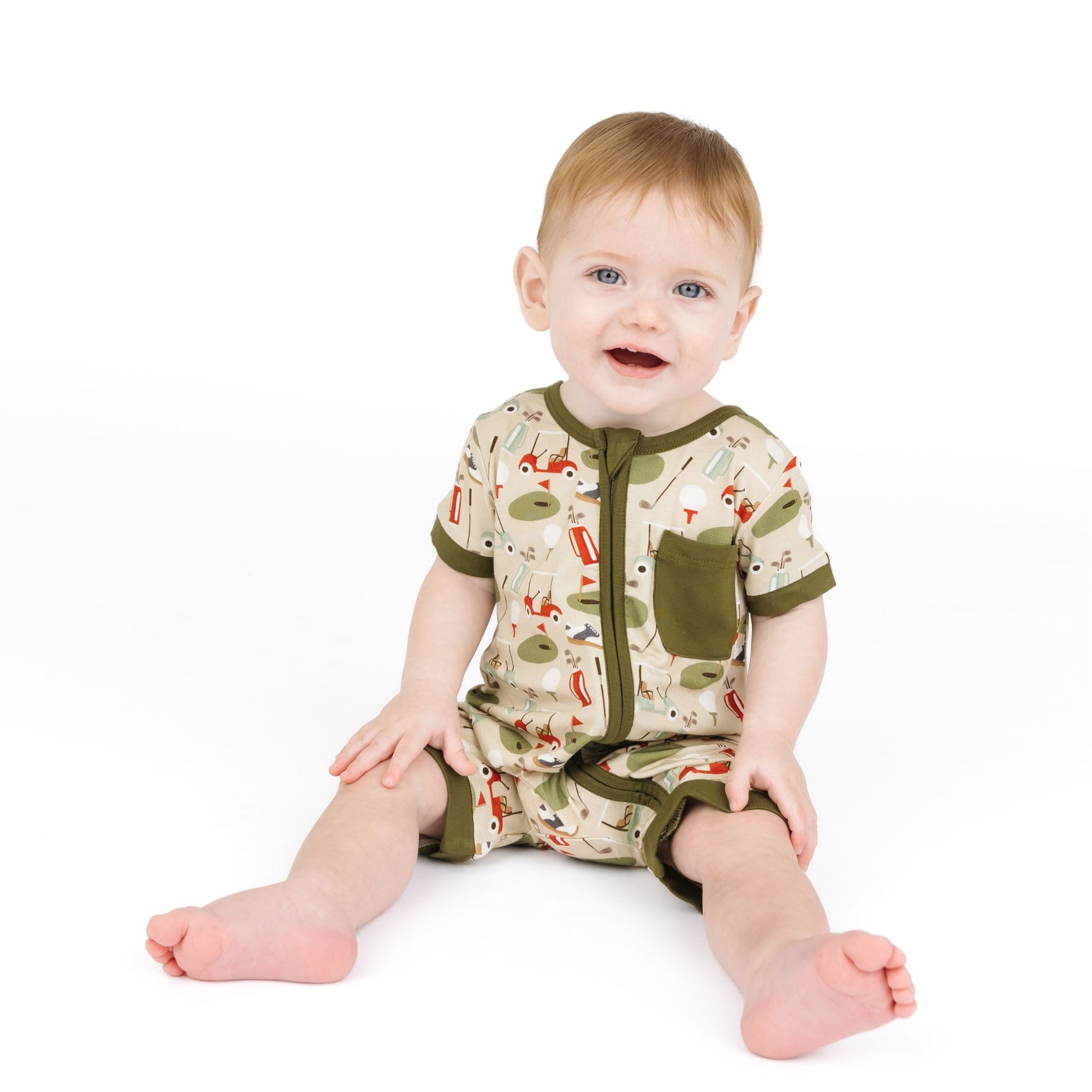 Baby wearing a patterned onesie with green trim on a white background