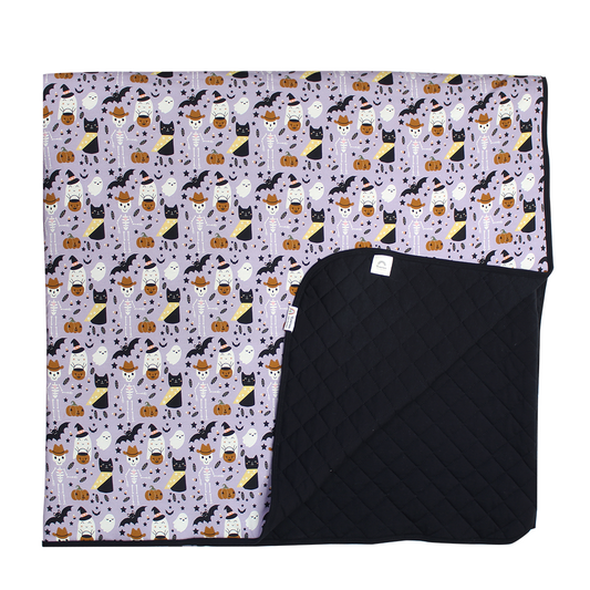 the "spooky cute purple" bamboo quilt blanket. the "spooky cute purple" print is a halloween themed pattern that contains cute versions go ghost, skeletons, black cats, candy treats, bats, and pumpkins. 