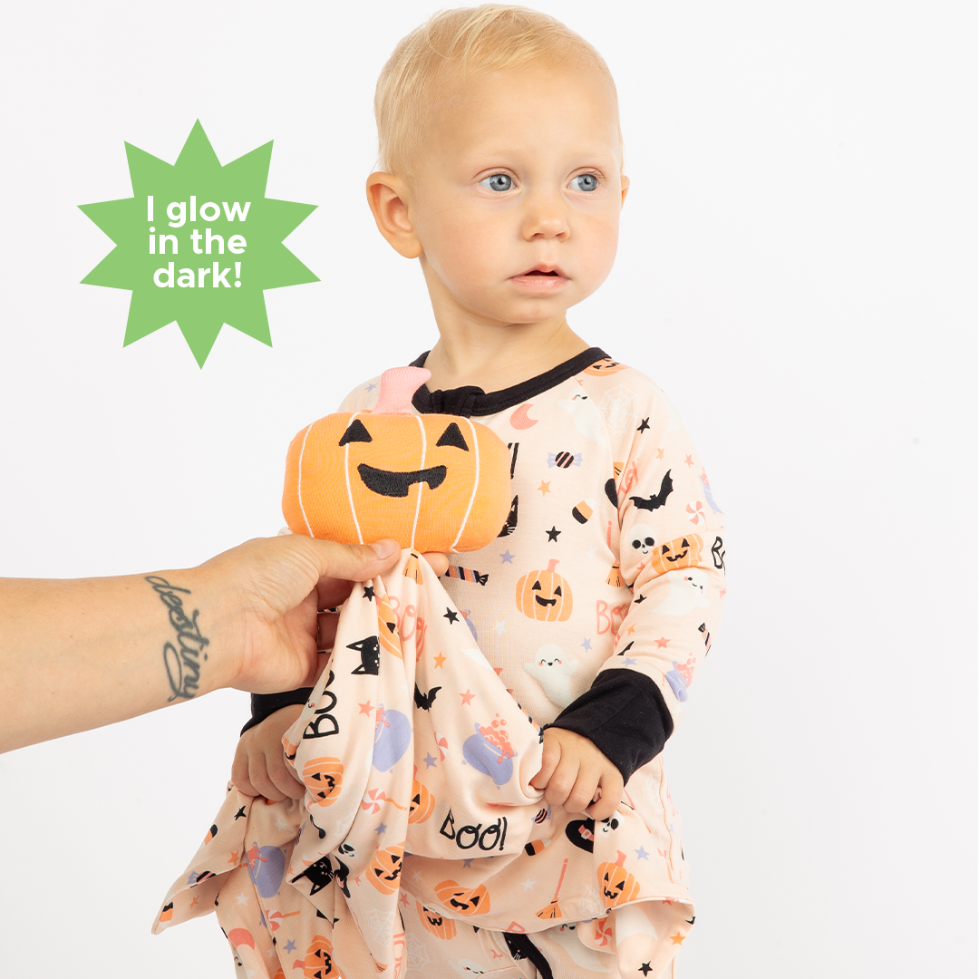 Girl modeling our baby convertible pajama while mom holds out the pumpkin lovey in  our Sweet and Spooky pink halloween Print featuring glow in the dark patterns, pumpkins, candy, bats and more!