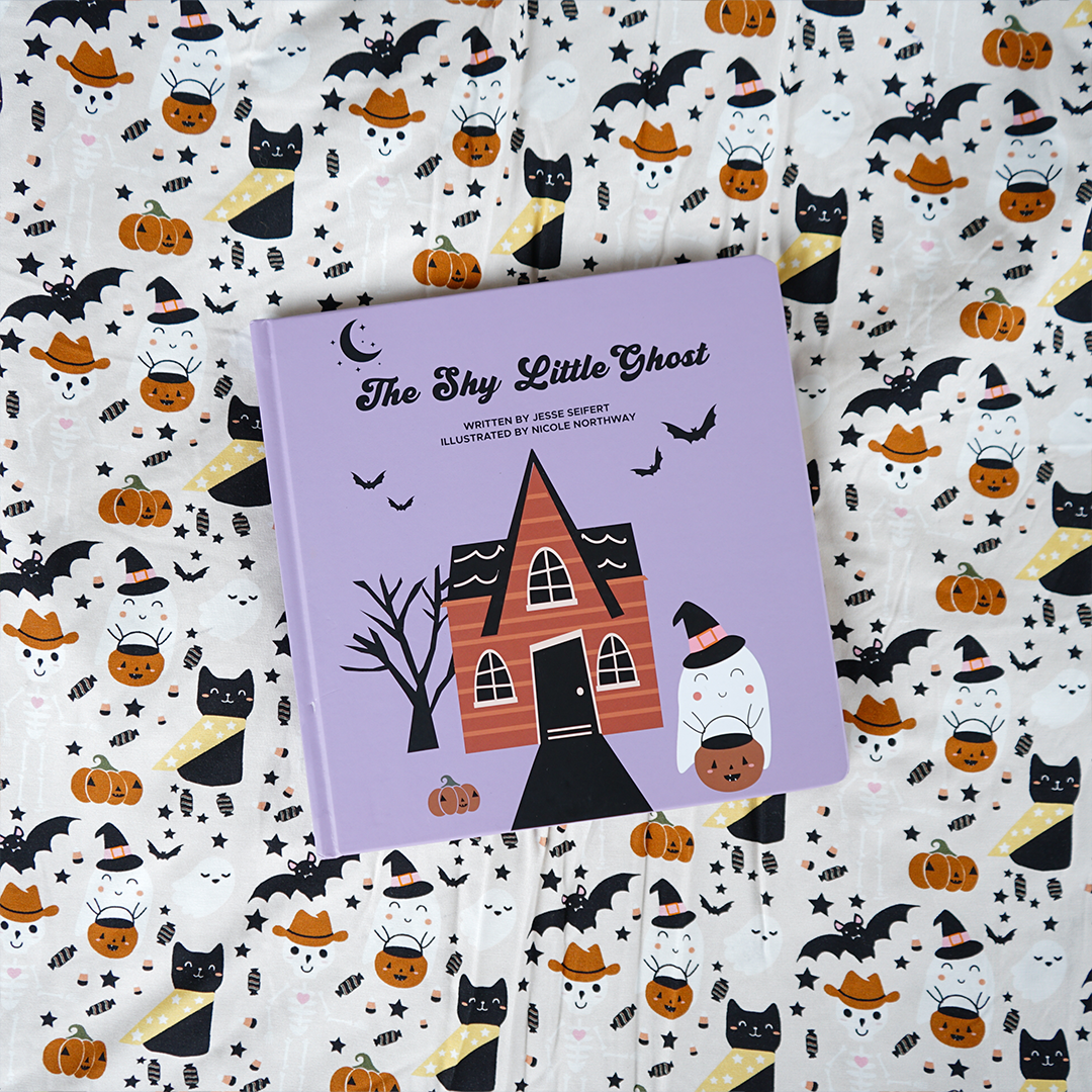 photo of the "shy little ghost" board book on top of the "spooky cute beige" blanket. 