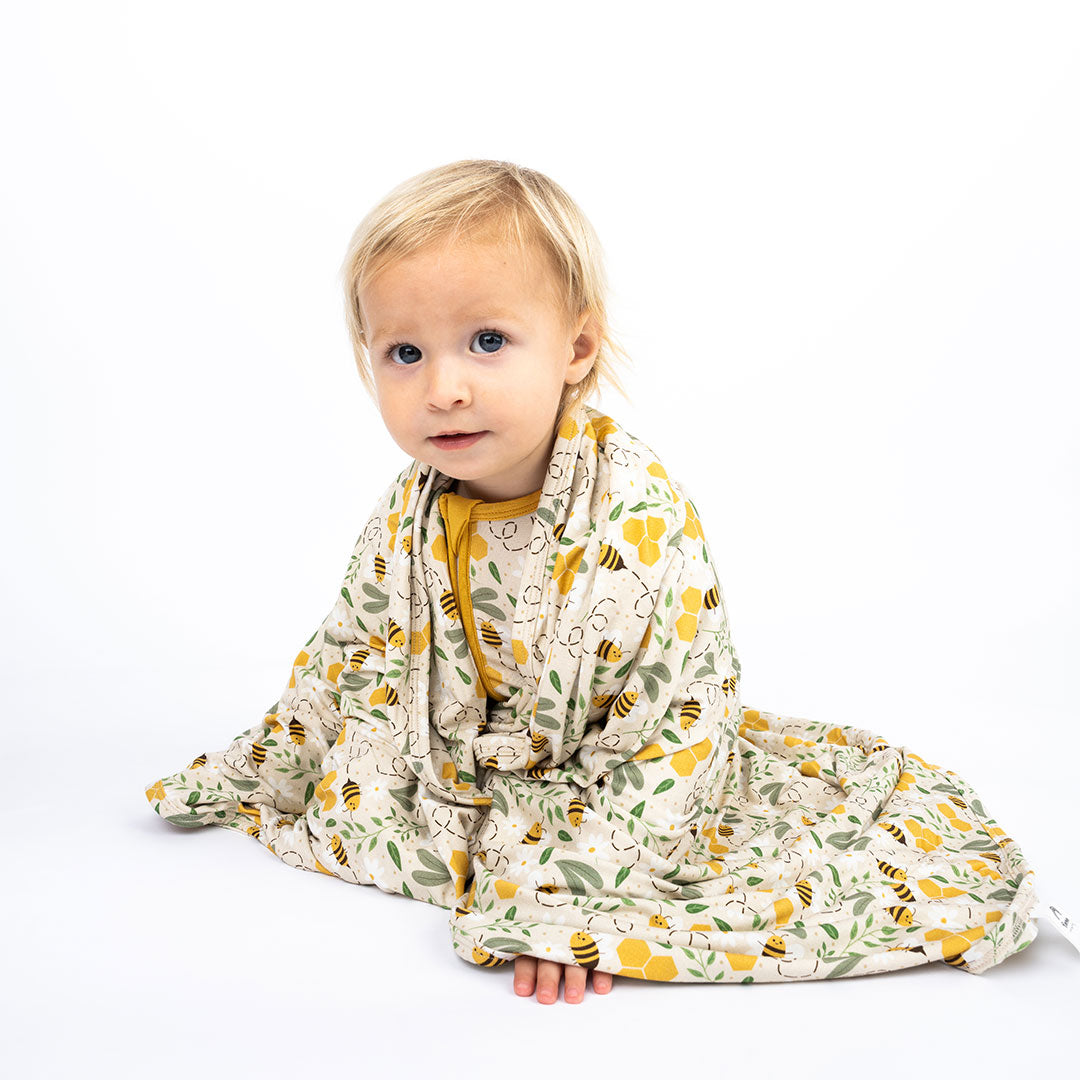 Happy Honey Bees luxury bamboo blanket by Emerson and Friends. This ultra-soft, breathable blanket features an adorable honey bee and honeycomb print, perfect for snuggles. Made from eco-friendly bamboo fabric, it’s gentle on sensitive skin and ideal for year-round comfort.