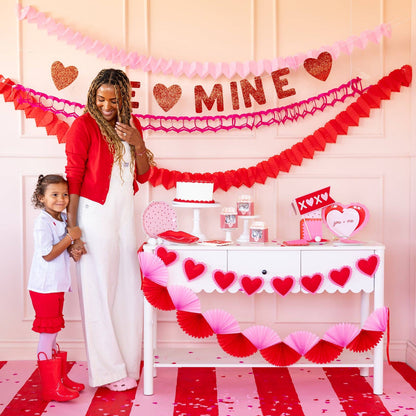 Woman and child in a room decorated for Valentine's Day with heart-themed decor.