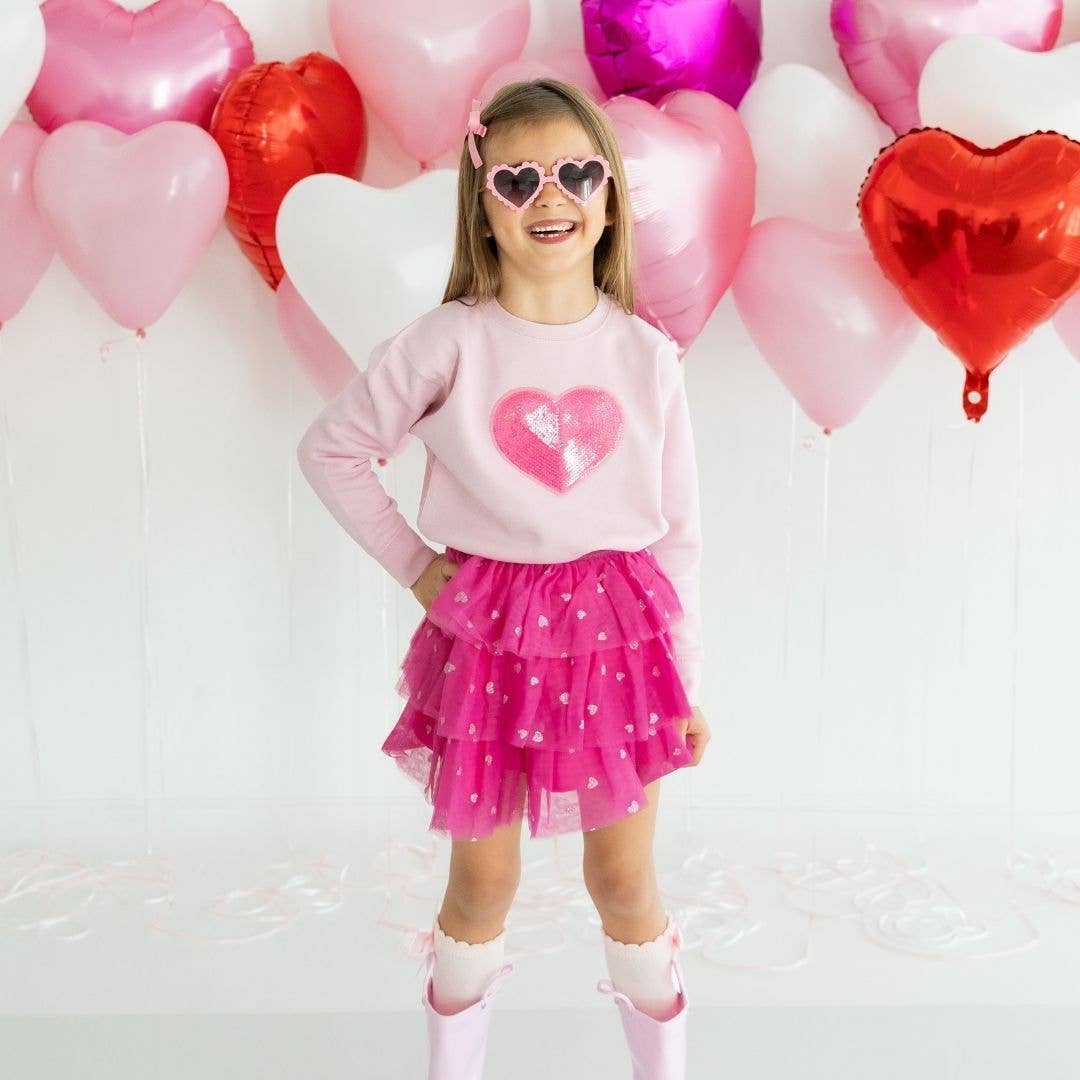 little girl wearing hot pink tutu with 3 layers of tulle and glittery hearts on it