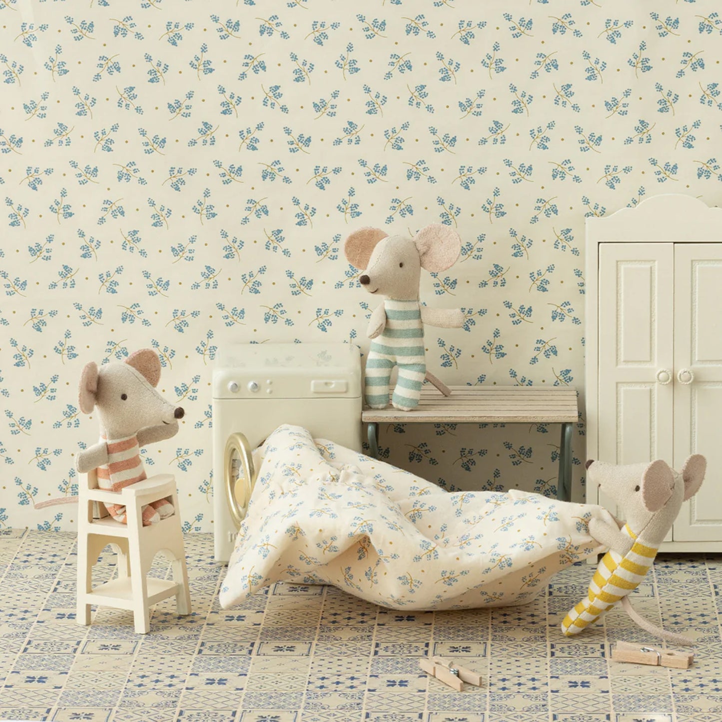 Children's room with floral wallpaper, toy mice, and a bed.