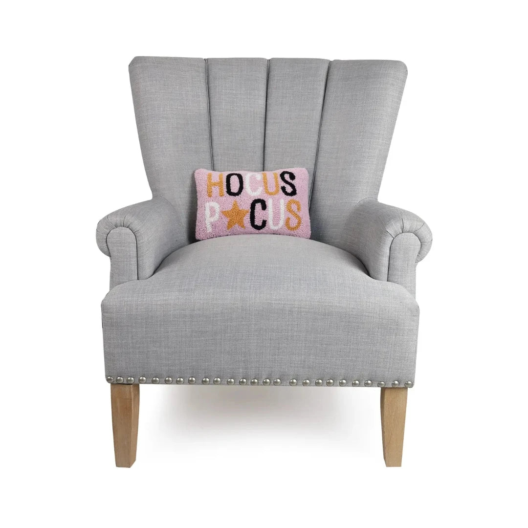 decorative arm chair with a pink pillow that says Hocus Pocus on the front