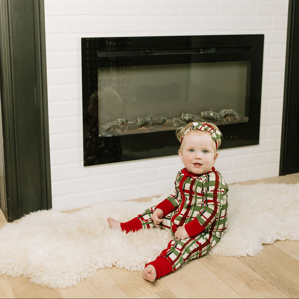Baby girl sitting in the floor wearing our Holiday Plaid Bamboo Baby Convertible