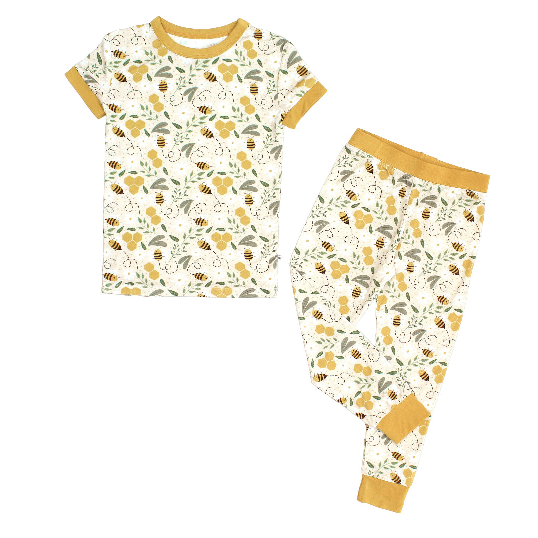 Two-piece bamboo kids' pajama set featuring a happy honey bee print with short sleeves and long pants. Made from ultra-soft, breathable, and hypoallergenic fabric, perfect for comfortable sleep year-round.