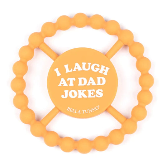 yellow baby teether ring that says i laugh at dad jokes on it
