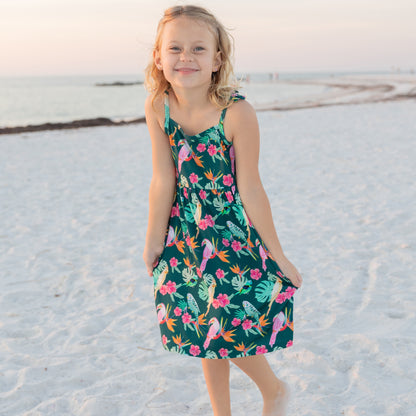 Front view of a girl wearing the botanical birds print sundress, highlighting the vibrant colors and soft, stretchy bamboo fabric.