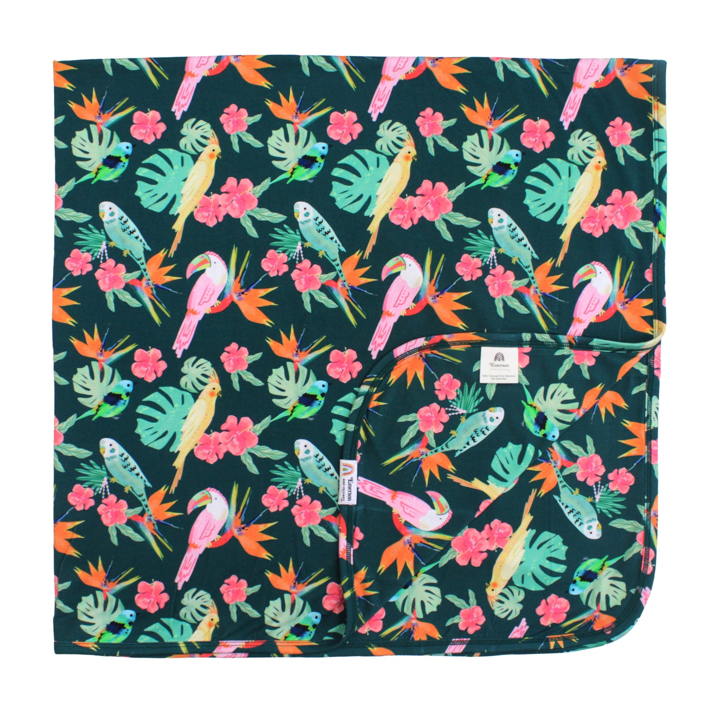 Double-layered luxury bamboo blanket in the Isla Botánica print featuring colorful tropical birds and lush palm leaves.