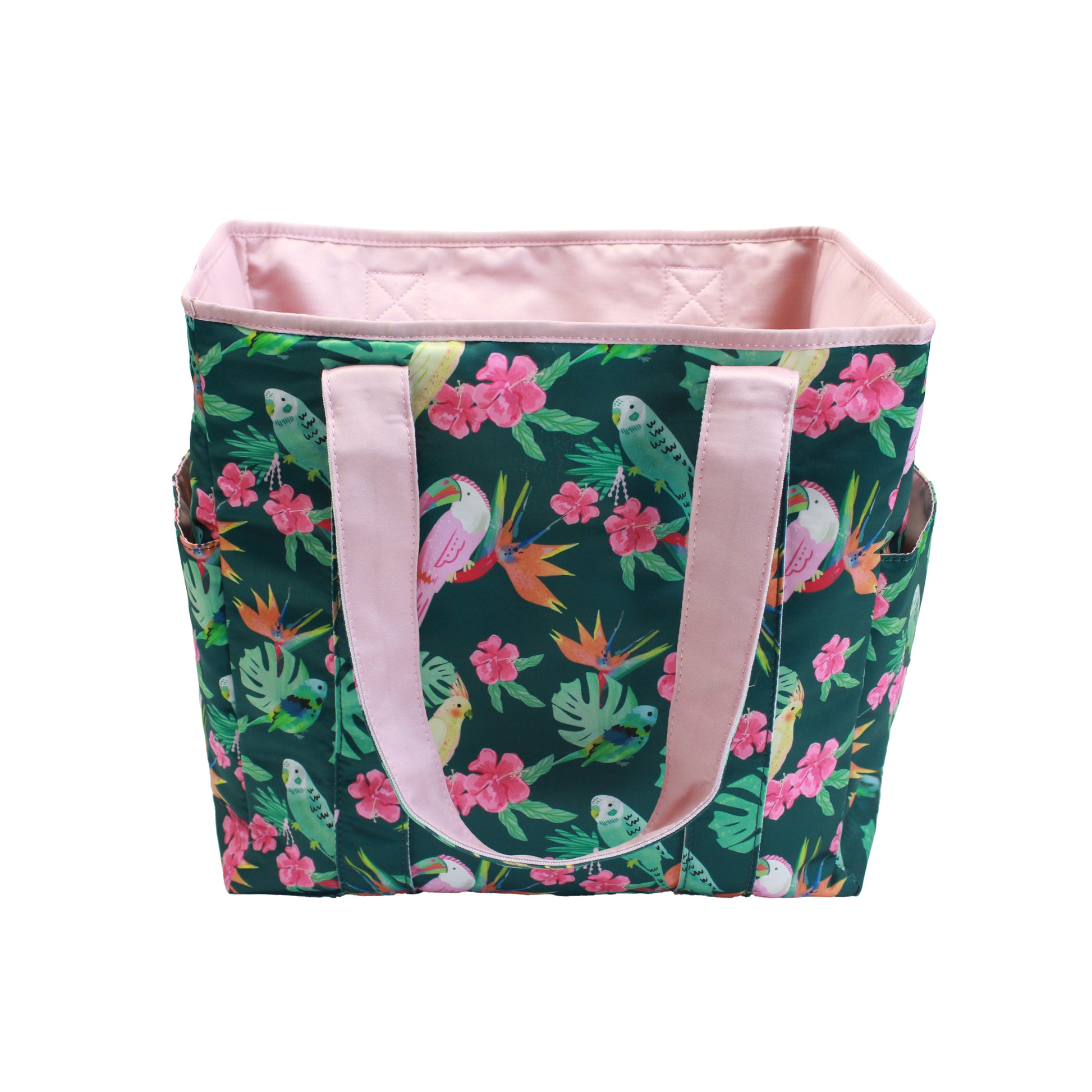 Large reversible beach bag in the Isla Botánica print featuring tropical birds and pink handles with a glimpse of the pink interior.