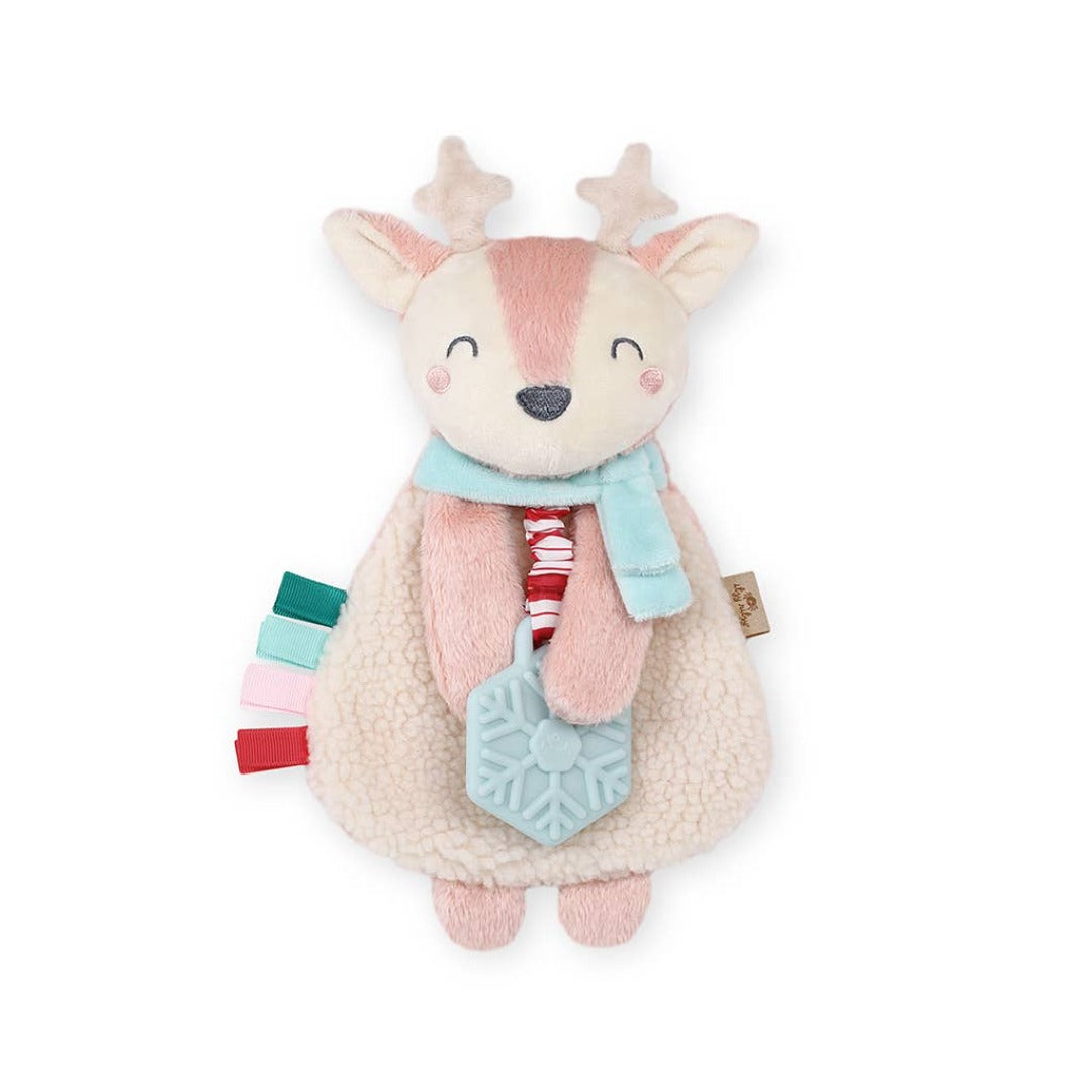 itzy the reindeer teether. pink and white reindeer with a blue scarf. the reindeer holds a blue snowflake. 